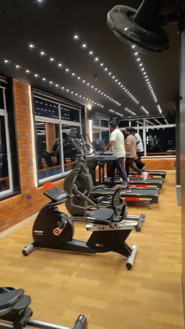 Cardio area with exercise bikes and treadmills beside brick-effect walls and windows