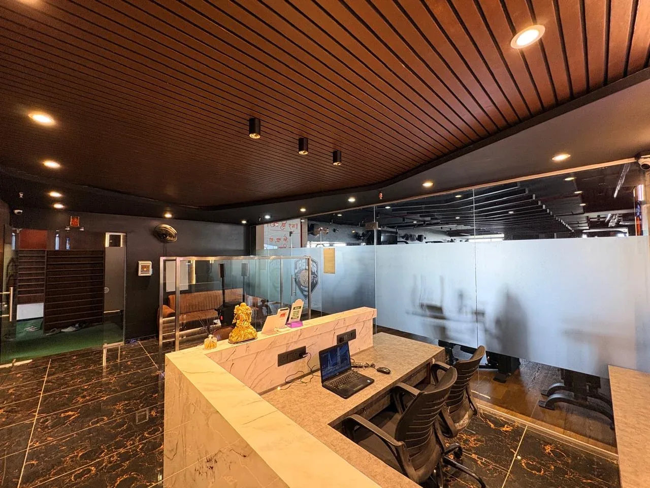 Reception desk beneath the wooden slatted ceiling at Jaguar Fitness Den